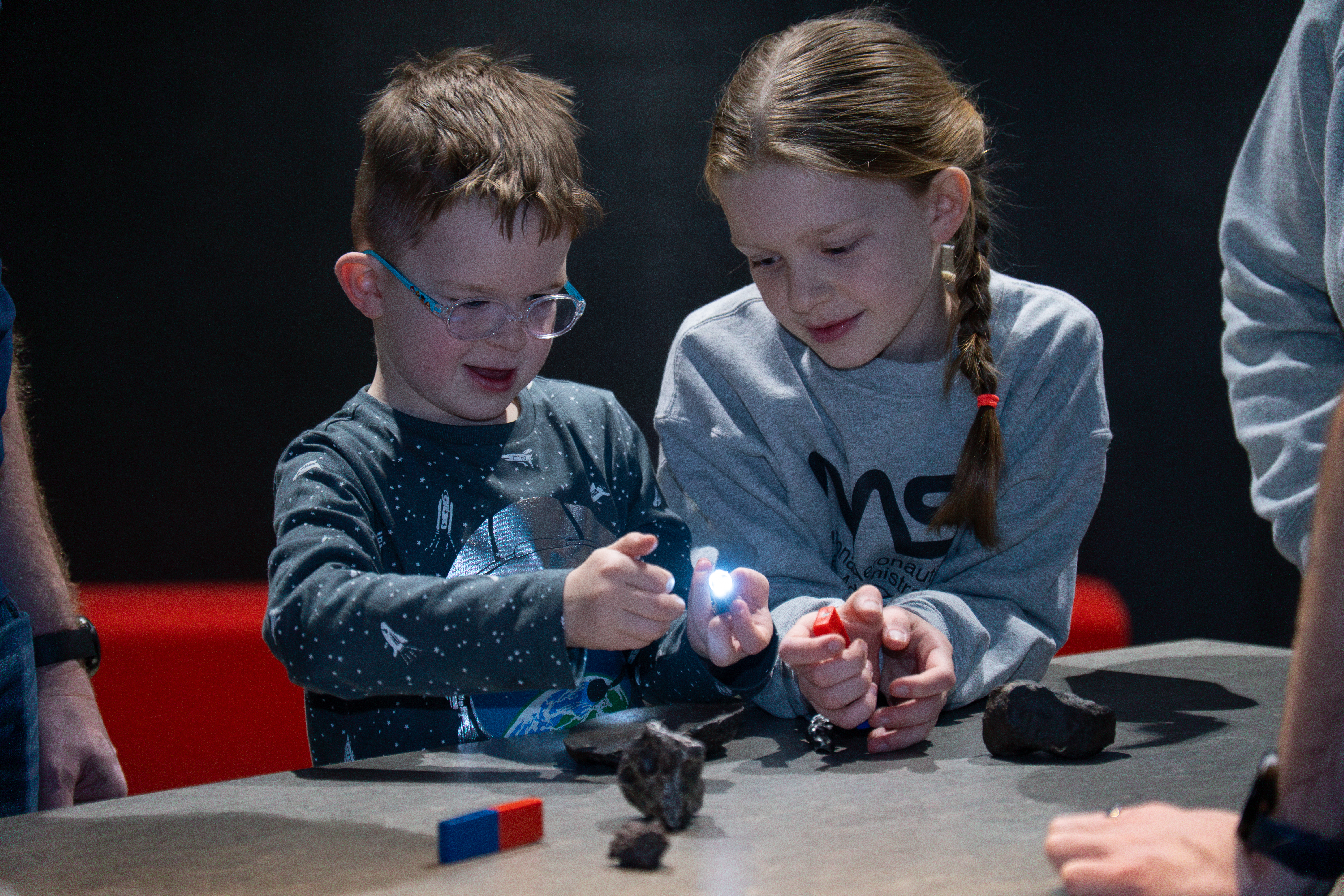 Two children are using magnets to test the materials in small meteorites